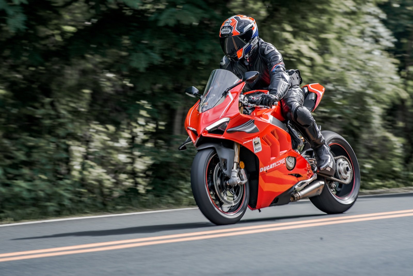 man in orange and black motorcycle suit riding on orange sports bike